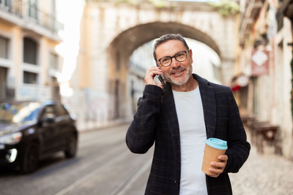 Man talking on phone holding coffee on city street of Portugal